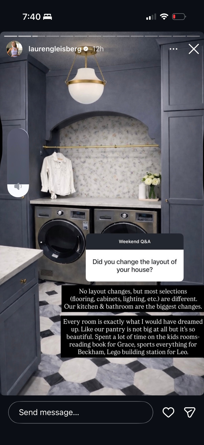 Laundry nook with deep blue cabinetry, floral wallpaper, globe lighting and a patterned floor.